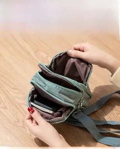 Detail view of the multi-zipper grey-green crossbody bag with three spacious compartments