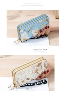 Detail of floral embroidered double zipper wallets in blue and cream with wrist strap