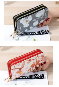 Close-up of dual zipper long wallet with floral prints and a branded LOVE wrist strap