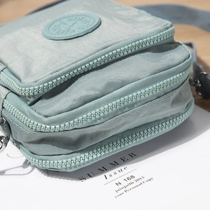 Multi-layer zippered crossbody bag in light grey-blue nylon with adjustable strap
