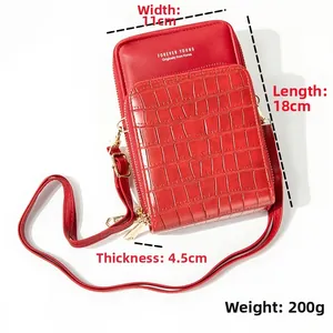 Macro shot of red crossbody phone bag featuring crocodile texture and gold hardware details