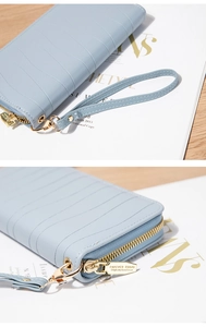 Detailansicht des goldenen Reißverschlusses und der Handschlaufe an einer blauen Geldbörse
