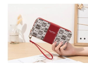 Détail du portefeuille long en cuir rouge et toile avec fermeture éclair et dragonne