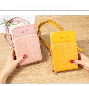 Detail of pink and yellow crossbody phone bags featuring crocodile pattern and zip pocket