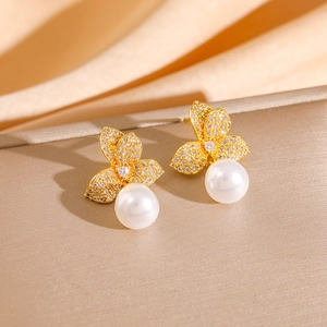 Elegant gold flower earrings with pavé crystals and pearl drops on silk background
