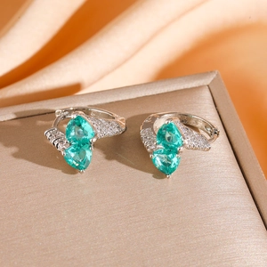Detail of silver hoop earrings with emerald green pear stones and white zircon accents