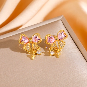 Orecchini a fiocco con cristallo rosa su un elegante portagioie in seta dorata