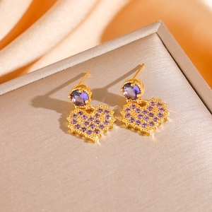 Golden heart earrings with purple crystals on a champagne silk jewelry box background