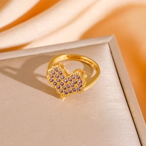 Macro shot of heart-shaped gold ring with purple micro-pave stones on brushed metal