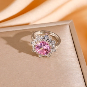 Macro view of adjustable silver ring with pink flower zircon on golden jewelry box