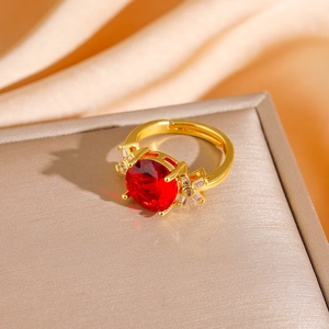 Detail of red round gemstone ring with clear zircon accents on a golden band