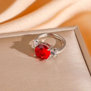 Macro shot of a red gemstone ring with side diamonds on a champagne silk background