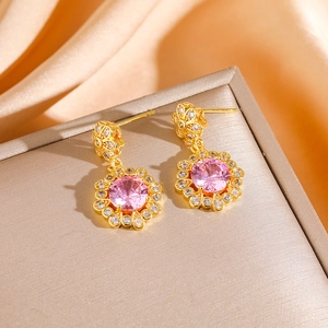 Macro shot of gold flower earrings featuring pink zircon centers and white crystal petals