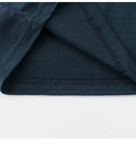 Détail de l'ourlet à double surpiqûre sur un t-shirt en coton bleu foncé pour enfants
