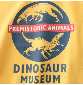 Detail of yellow cotton fabric showing retro prehistoric dinosaur museum graphic print