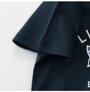 Dettaglio cucitura a doppio ago su manica di T-shirt in cotone blu scuro e tessuto