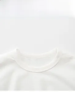 Close-up of ribbed crew neck and shoulder stitching on white cotton kids t-shirt
