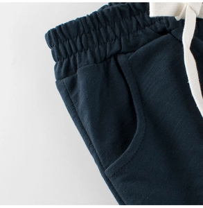 Detalle de los pantalones cortos de punto azul marino para niños con cordón blanco