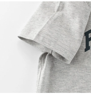Detail van dubbele naaldstiksels en stoftextuur op een grijs katoenen t-shirt voor kids