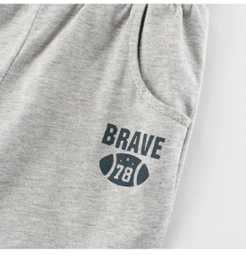 Detailopname van grijze kinderbroek met Brave 78 print en de textuur van de stof