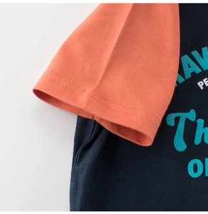 Detail of raglan sleeve stitching and printed blue lettering on navy cotton T-shirt