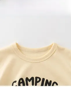 Detail of crew neck stitching and bold black camping print on beige cotton kids t-shirt