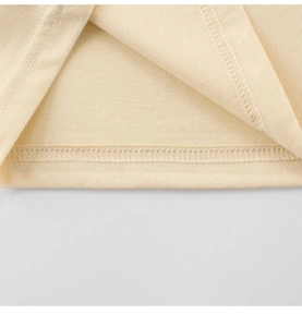 Close-up of neatly stitched double-needle hem on kids' cotton beige t-shirt