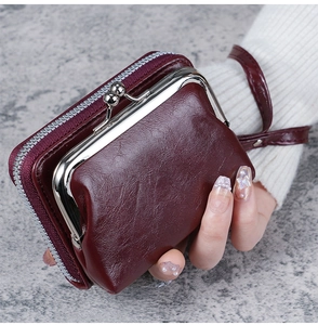Close-up of wine red textured leather wallet with metal clasp and wrist strap detail