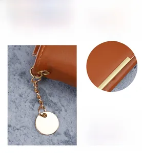 Detail of brown faux leather wallet featuring gold chain pendant and metal hardware