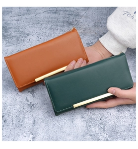 Detail of leather long wallets in caramel and green with elegant gold metal trim bar