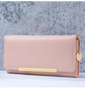 Detailed view of pink leather long wallet with gold bar trim and delicate metal chain charm