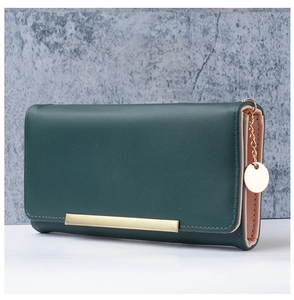 Detail of green and pink leather long wallet with gold accents and metal charm