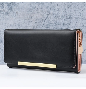 Detail of a black long wallet featuring gold metal trim and pink multi-slot interior layers