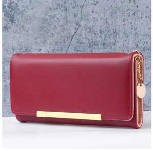 Detail of burgundy leather wallet with gold metal trim and round logo pendant charm