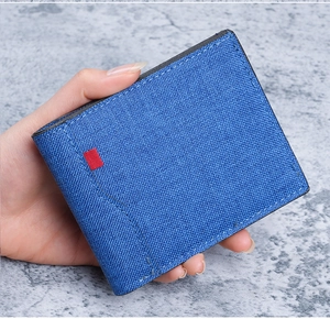 Nahaufnahme einer blauen Canvas-Geldbörse mit rotem Logo-Patch in der Hand