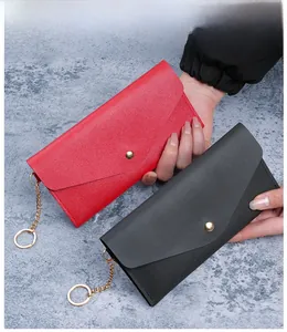 Detail of minimalist leather texture and gold snap closure on red and black long wallets