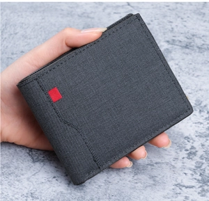 Herren-Brieftasche aus strukturiertem Canvas mit rotem Etikett, handgehalten zur Ansicht