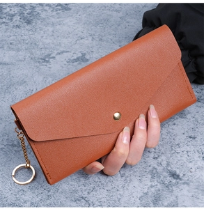 Detail of tan pebble leather long wallet with gold snap button and chain attachment