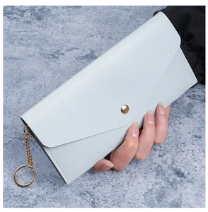 Detail of light blue pebble leather long wallet with gold snap button and metal chain