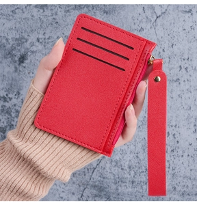 Detail of red slim card holder featuring litchi texture and golden zipper with wrist strap