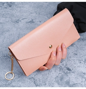 Detailed view of pink leather long wallet with snap button and gold chain keychain accessory