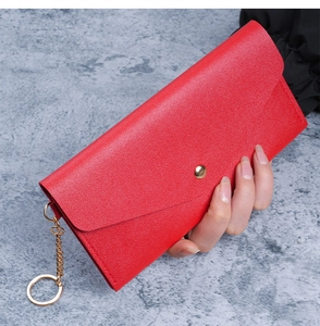 Detail of red pebbled leather long wallet with gold snap button and metal chain strap