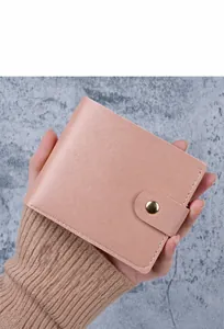Detail of light pink pebble leather wallet with white stitching and snap button