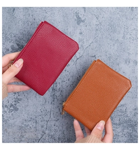 Close-up of litchi grain leather wallets in burgundy and orange with gold zipper