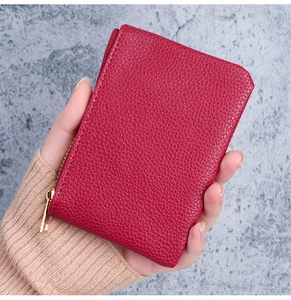 Close-up of a small red lychee grain leather wallet held in hand with golden zipper