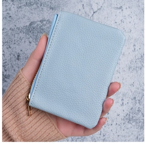 Close-up of light blue pebble leather mini wallet with gold zipper detail
