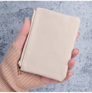 Close-up of a beige lychee texture leather mini wallet with gold zipper detail