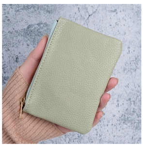 Close-up of light green lychee texture leather wallet with gold zipper detail
