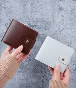 Detail of compact bi-fold wallets in brown and light blue with gold snap buttons