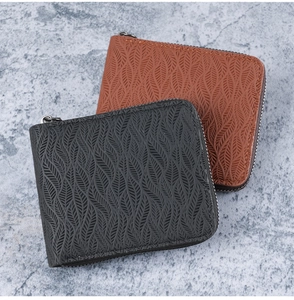 Detail of embossed leaf texture on black and brown men's zip wallets with metal zippers